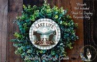 A wreath made of green foliage and a circular sign with the text "Lake Life" and an image of a lake and chairs.