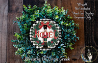 A wreath made of green leaves and a nutcracker figure, with the word "Noel" displayed on it. The wreath is placed on a wooden surface.
