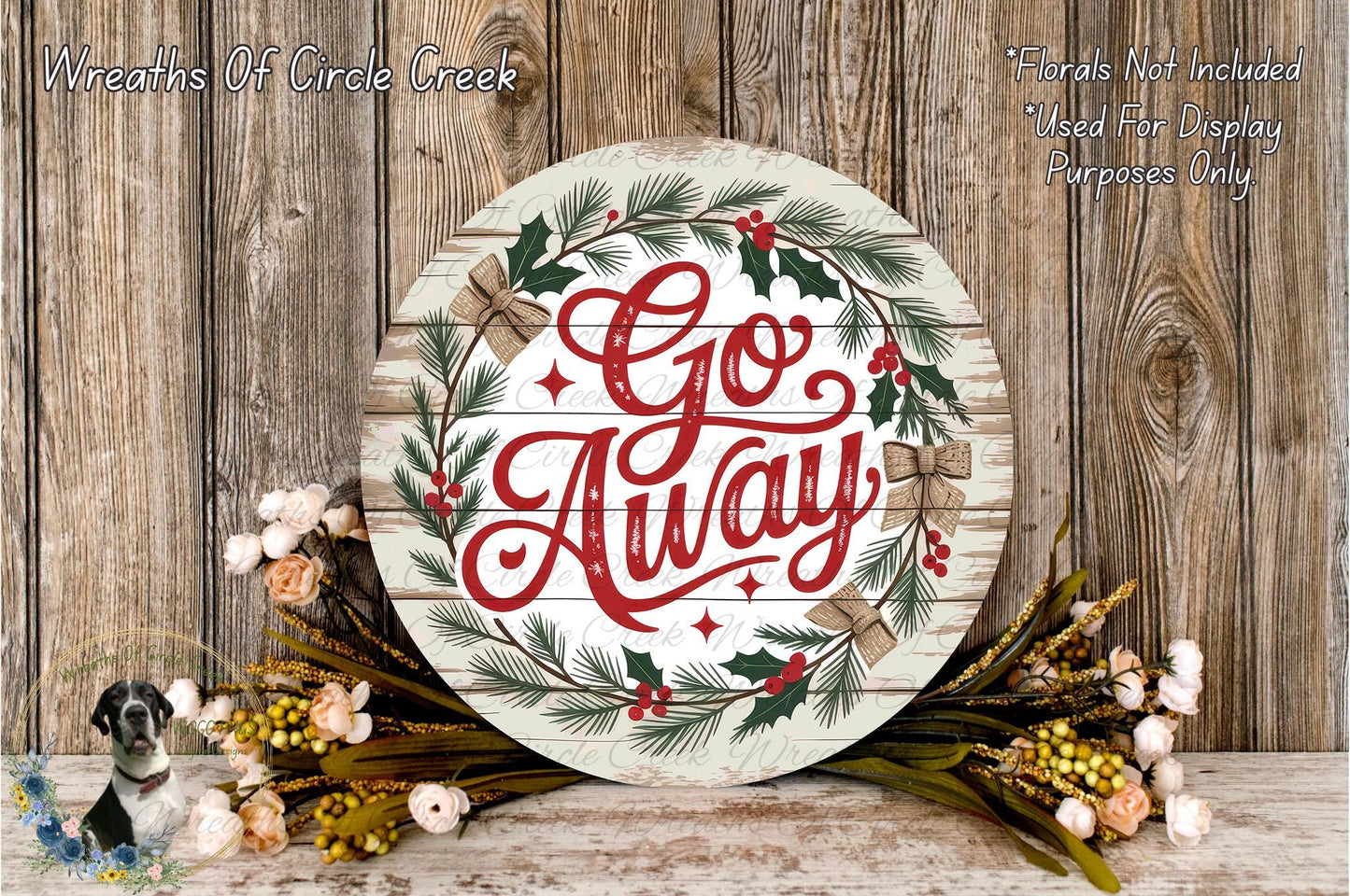 a round wooden sign with the text "Go Away" written on it, surrounded by a wreath of greenery and flowers. The sign is placed on a wooden surface, and there are additional floral arrangements nearby.