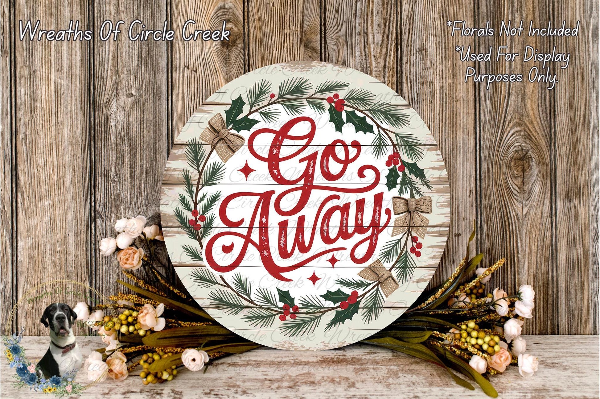 a round wooden sign with the text "Go Away" written on it, surrounded by a wreath of greenery and flowers. The sign is placed on a wooden surface, and there are additional floral arrangements nearby.