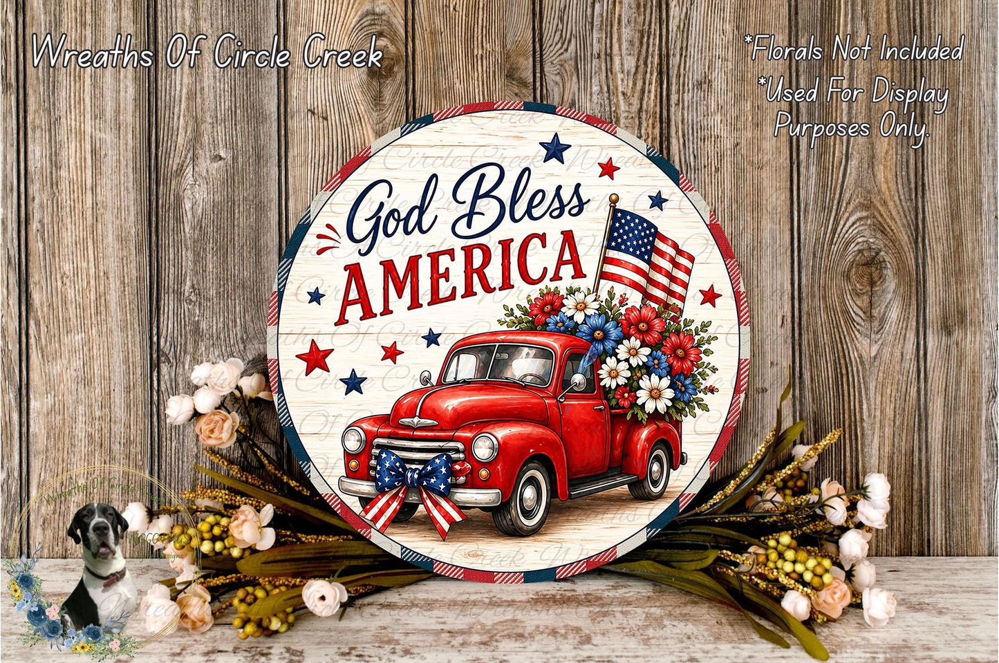 A circular sign with a red truck and American flags, surrounded by flowers, against a wooden background.