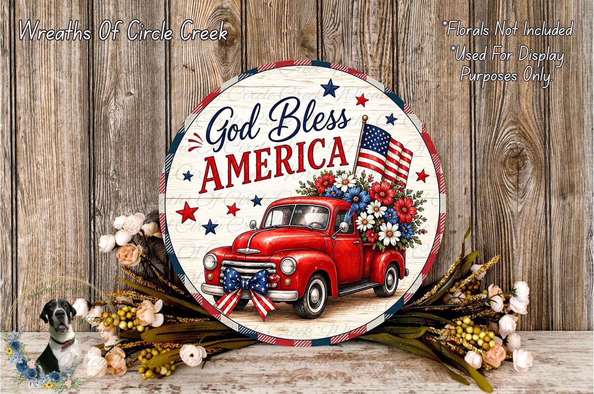 A circular sign with a red truck and American flags, surrounded by flowers, against a wooden background.