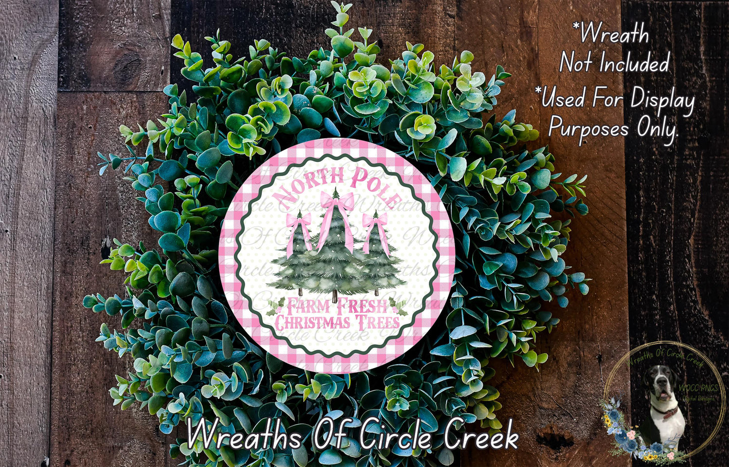 a wreath made of green foliage and a circular sign with a Christmas tree design, placed on a wooden surface.