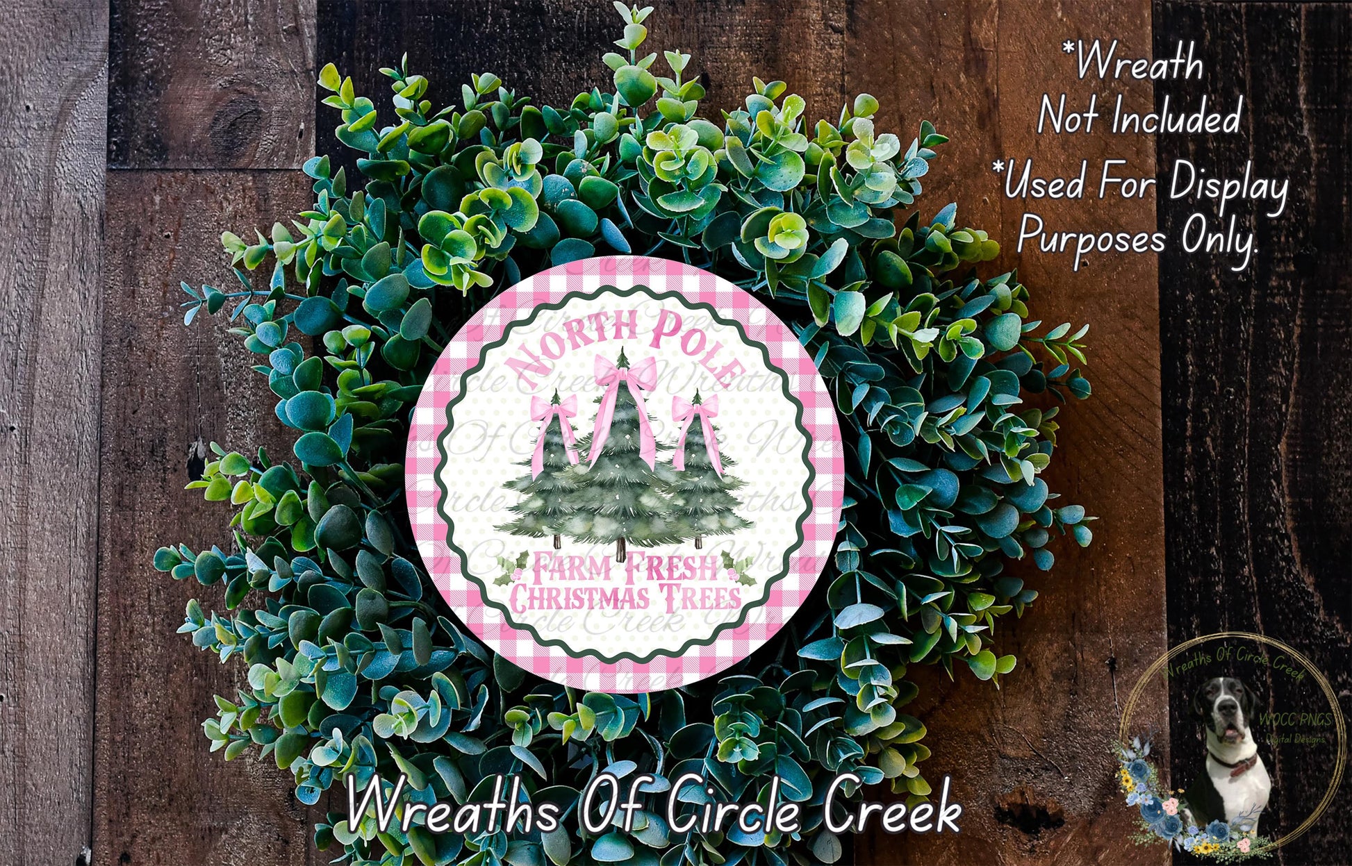 a wreath made of green foliage and a circular sign with a Christmas tree design, placed on a wooden surface.