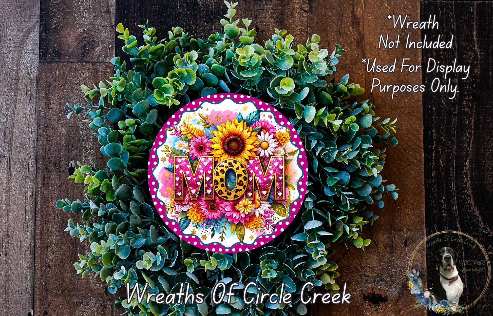 A wreath made of various green plants and flowers, with the word "MOM" prominently displayed in the center.