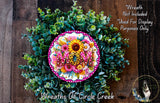 A wreath made of various green plants and flowers, with the word "MOM" prominently displayed in the center.