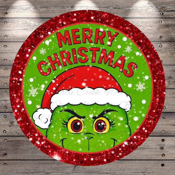 A circular Christmas-themed design featuring a grumpy-looking green creature wearing a Santa hat, surrounded by snowflakes and the text "MERRY CHRISTMAS".
