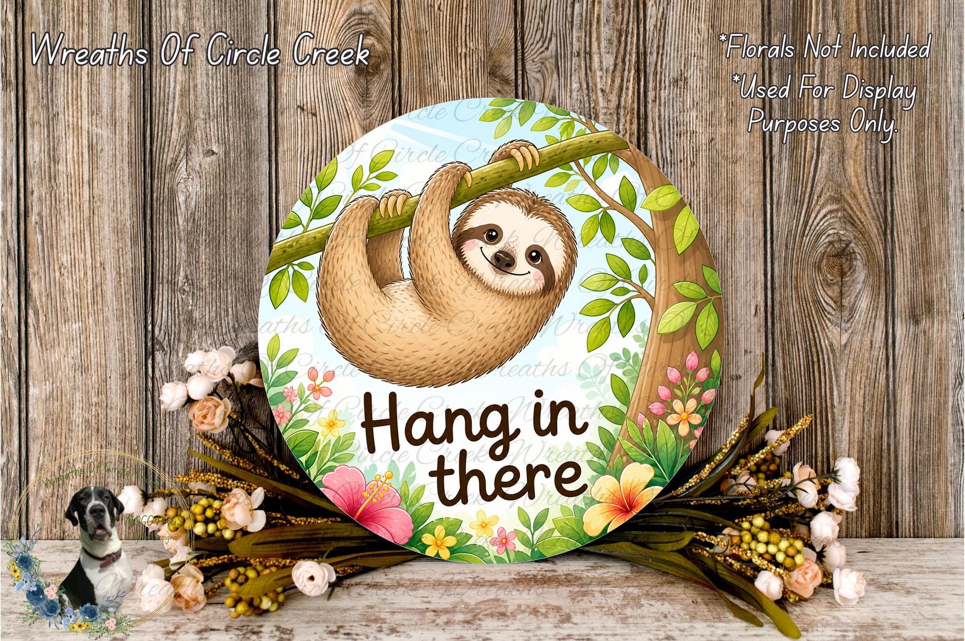 A round sign with a sloth hanging from a branch, surrounded by flowers and greenery, with the text "Hang in there" on it.