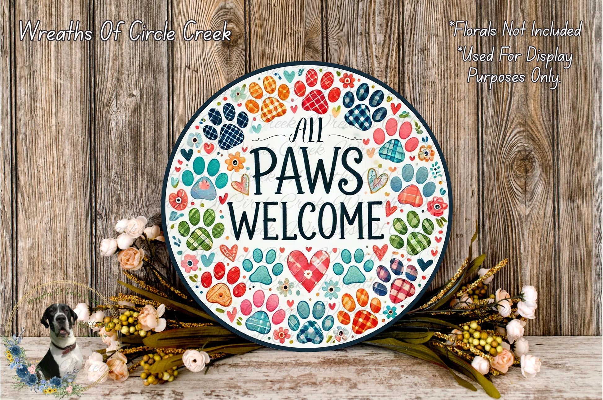 a decorative sign with the text "All Paws Welcome" surrounded by colorful paw prints and flowers, placed on a wooden surface.
