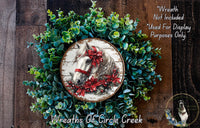 A wreath made of green leaves and a white horse with a red bow on its head, placed on a wooden surface.