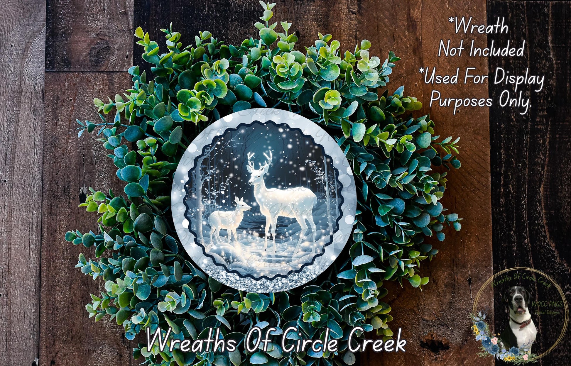 A wreath made of green leaves and a silver circular frame containing a photograph of two deer in a snowy forest.