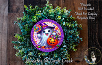 A wreath made of green leaves and a purple circle with a cartoon ghost holding a lollipop and a pumpkin.