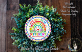 A wreath made of green leaves and flowers, with a colorful sign that reads "It's OKAY TO BE DIFFERENT #autismawareness" in the center.