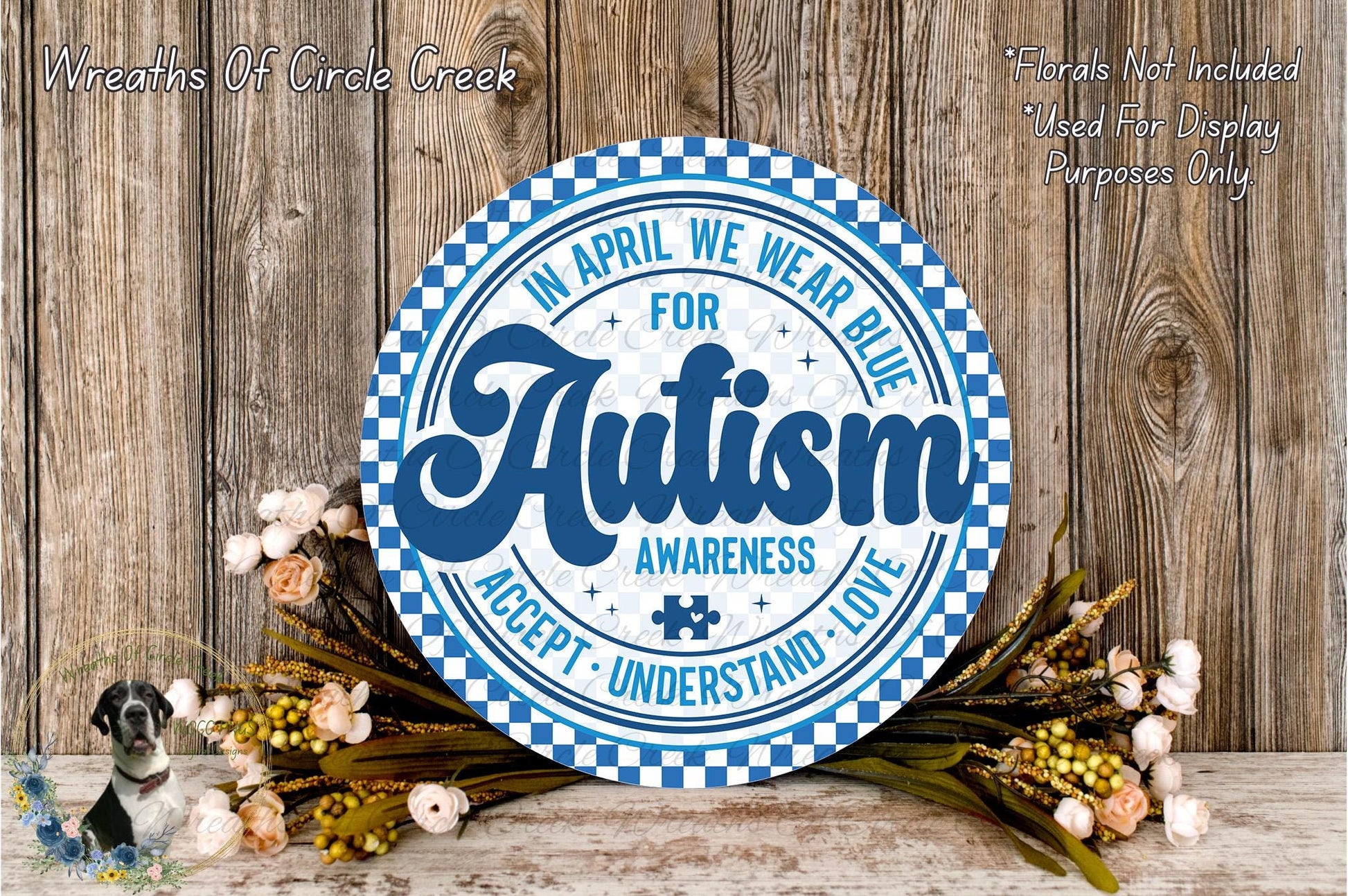 a round sign with a blue and white checkered pattern, surrounded by a floral arrangement on a wooden surface.