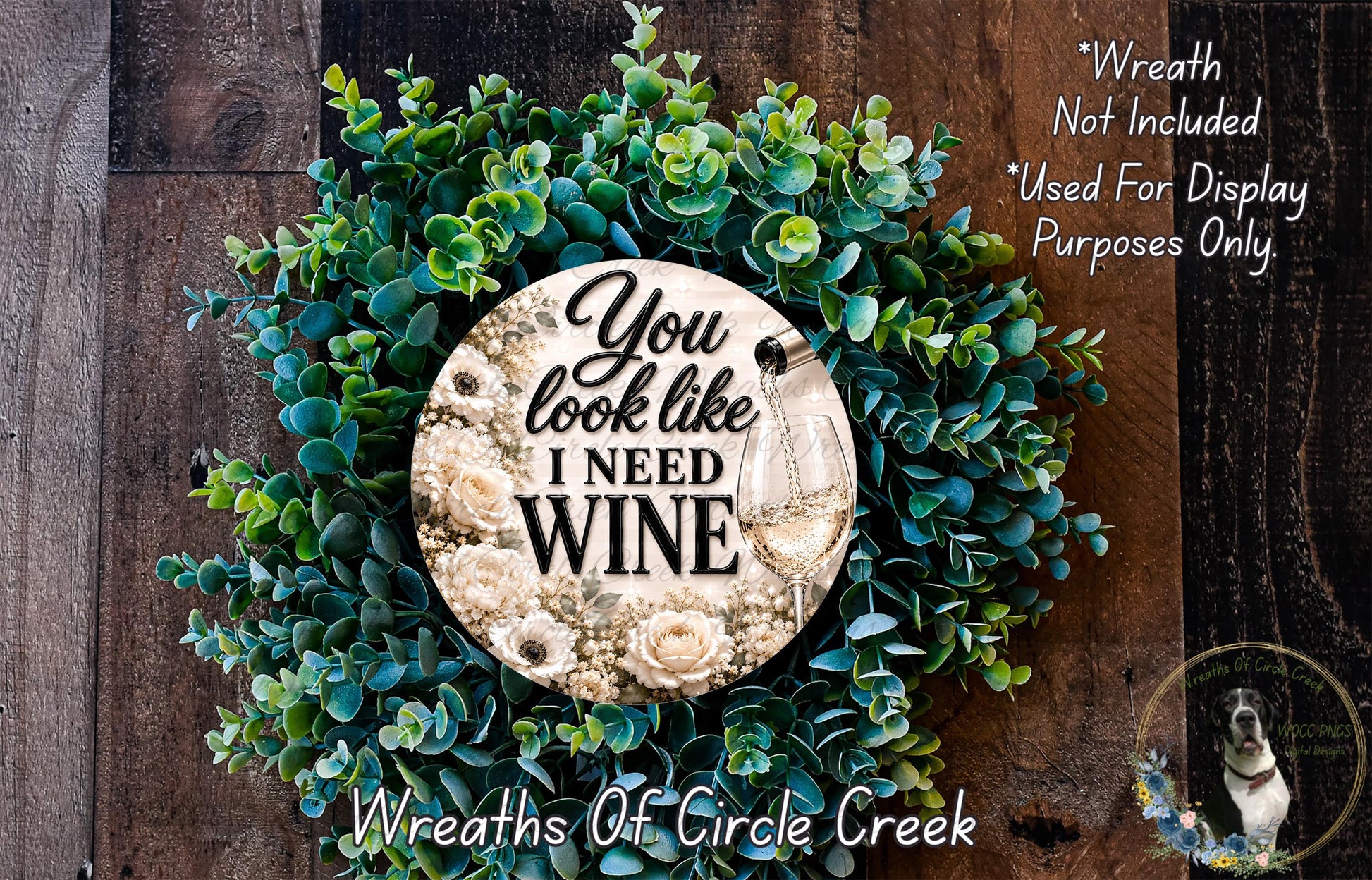 a wreath made of green leaves and flowers, with a circular sign in the center that says "You look like I need wine".