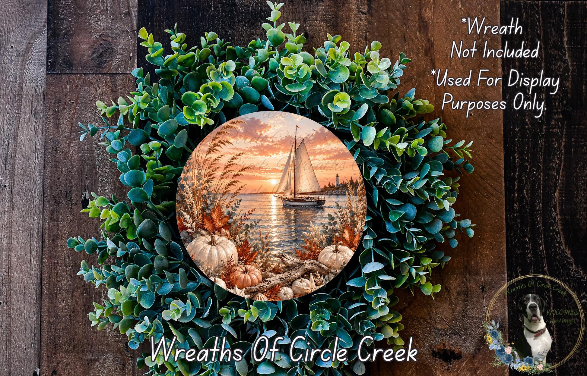 A wreath made of green leaves and pumpkins, with a circular painting of a sailboat on the water in the center.