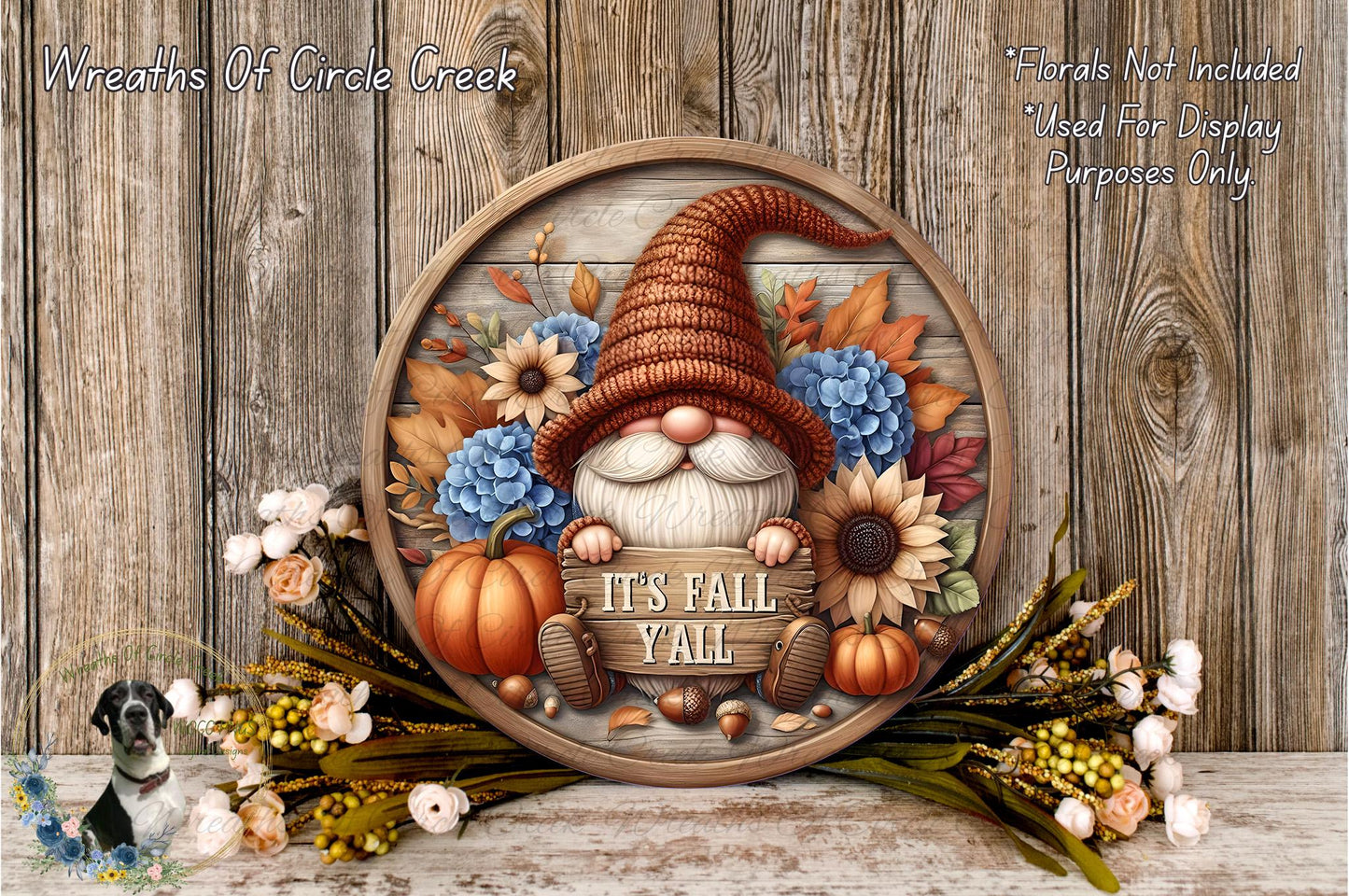 A decorative wreath featuring a gnome wearing a brown hat and surrounded by autumn-themed elements such as pumpkins, sunflowers, and flowers. The wreath is displayed on a wooden surface, and the text "It's Fall Yell" is written on it.
