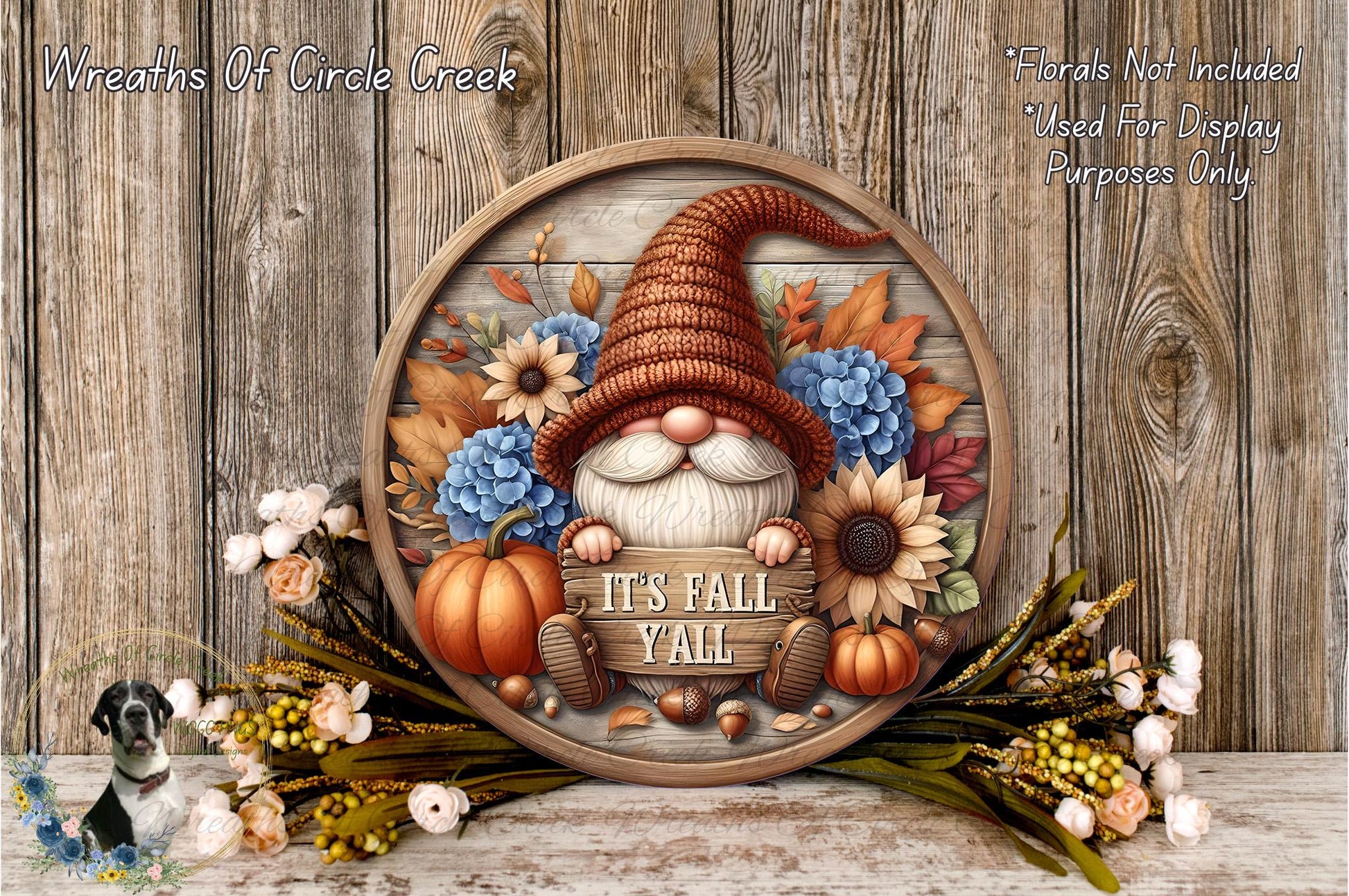 A decorative wreath featuring a gnome wearing a brown hat and surrounded by autumn-themed elements such as pumpkins, sunflowers, and flowers. The wreath is displayed on a wooden surface, and the text "It's Fall Yell" is written on it.