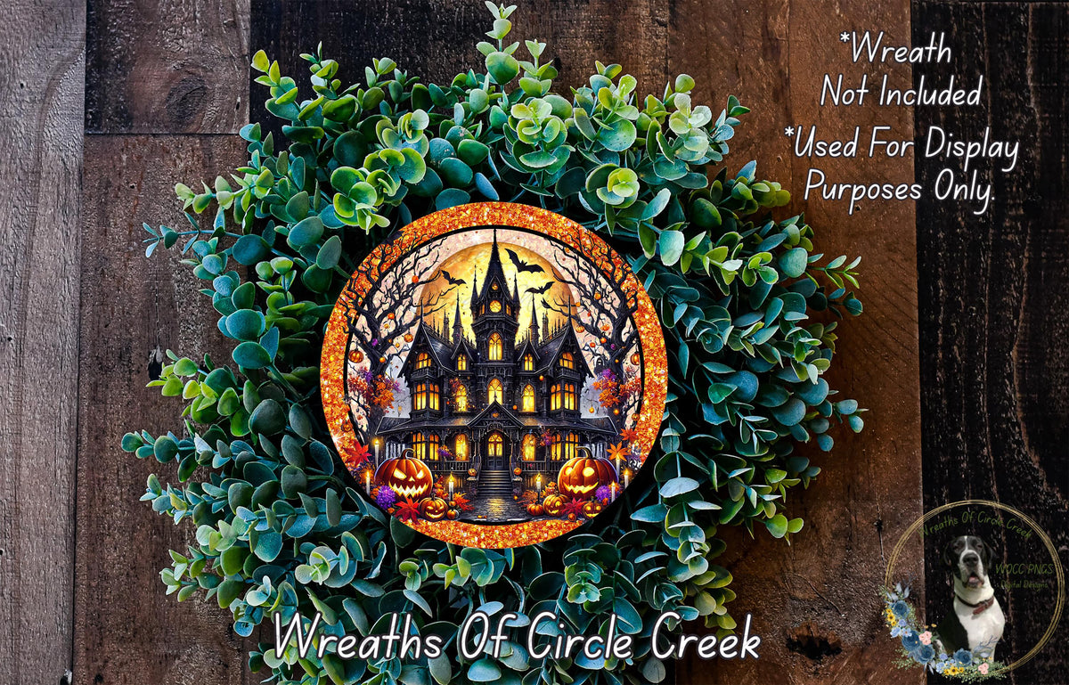 A Halloween-themed wreath made of green foliage and featuring a large, ornate house with a spire, surrounded by bats and pumpkins.