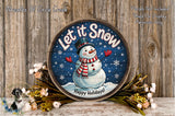 A round wooden sign with a snowman and the text "Let it Snow" is displayed on a wooden surface, surrounded by flowers and greenery.