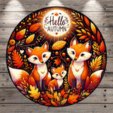 A vibrant illustration featuring three cartoon foxes surrounded by autumn foliage, including leaves, berries, and a glowing moon. The text "Hello Autumn" is prominently displayed above the foxes.
