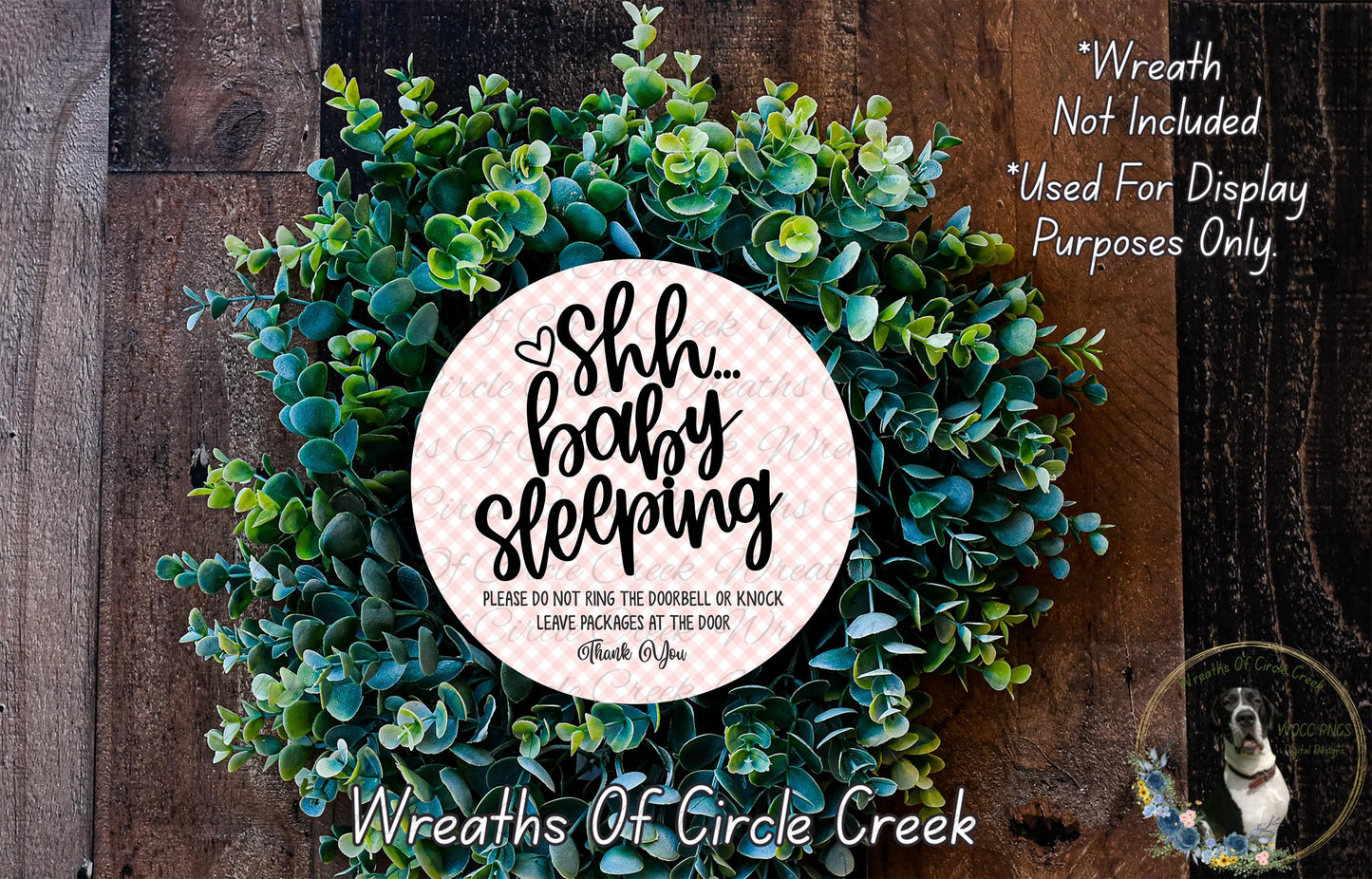 a wreath made of green leaves and a circular sign with text on it, placed on a wooden surface.