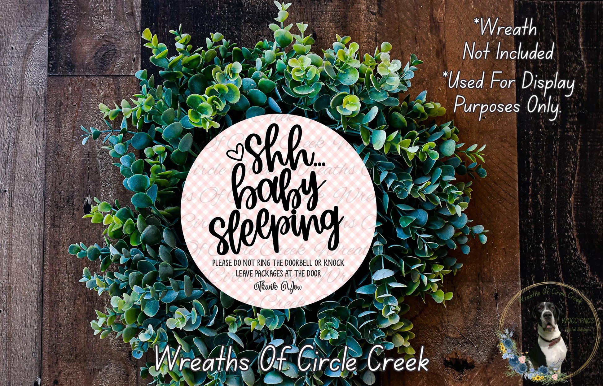 a wreath made of green leaves and a circular sign with text on it, placed on a wooden surface.