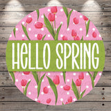 A circular design with a pink background featuring a pattern of pink tulips and green leaves. The text "Hello Spring" is prominently displayed in the center of the design.