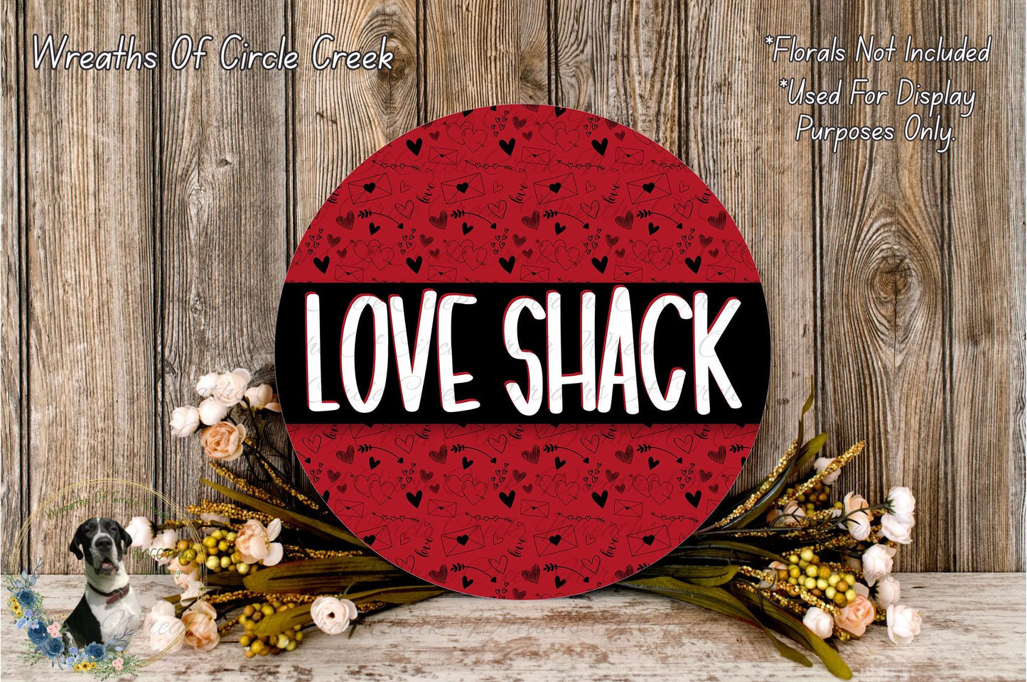 a red circular sign with the word "LOVE SHACK" written on it, surrounded by a floral arrangement and a wooden background.
