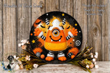 A whimsical, hand-painted monster with a candy cane hat and a big smile, surrounded by a floral arrangement and a wooden background.