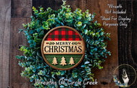 A Christmas wreath made of evergreen branches and a circular sign with the text "MERRY CHRISTMAS" in a rustic wooden background.