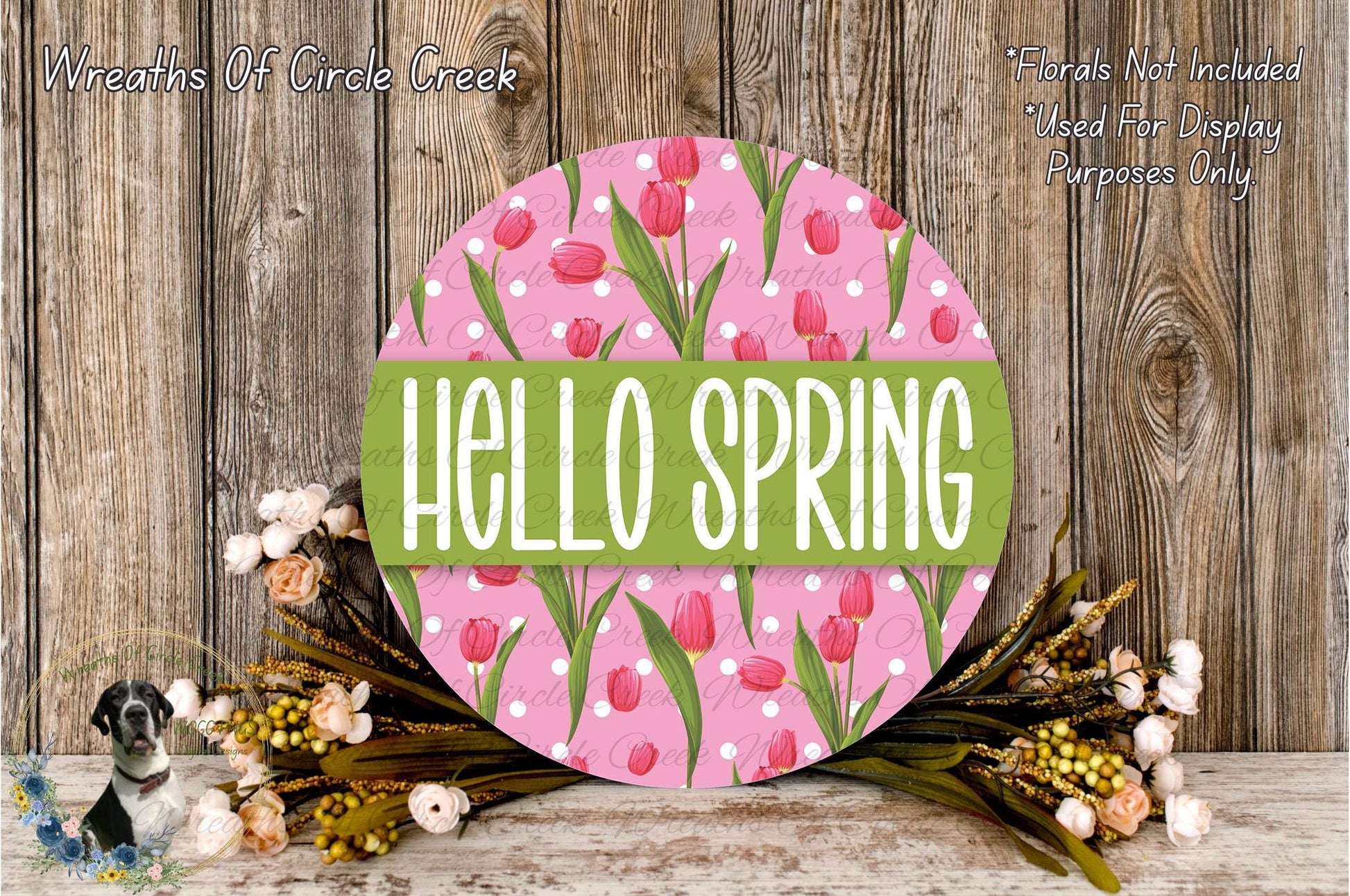 a circular sign with the text "Hello Spring" in a pink and green floral design, surrounded by a wreath of flowers and greenery.