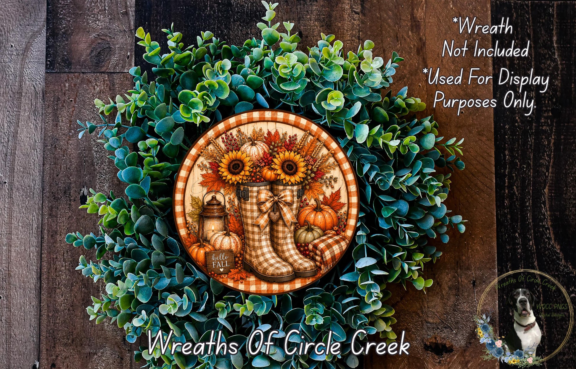 a wreath made of various fall-themed elements, including sunflowers, pumpkins, and a pair of plaid boots. The wreath is displayed on a wooden surface, and there is a small dog in the bottom right corner of the image.