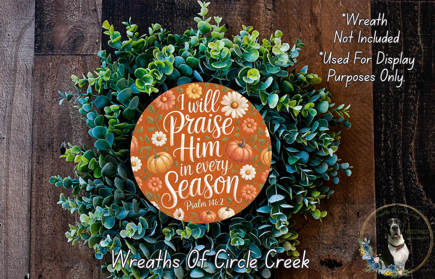 a wreath made of green leaves and orange pumpkins, with a circular orange sign in the center that reads "I will praise Him in every season" and a dog in the bottom right corner.