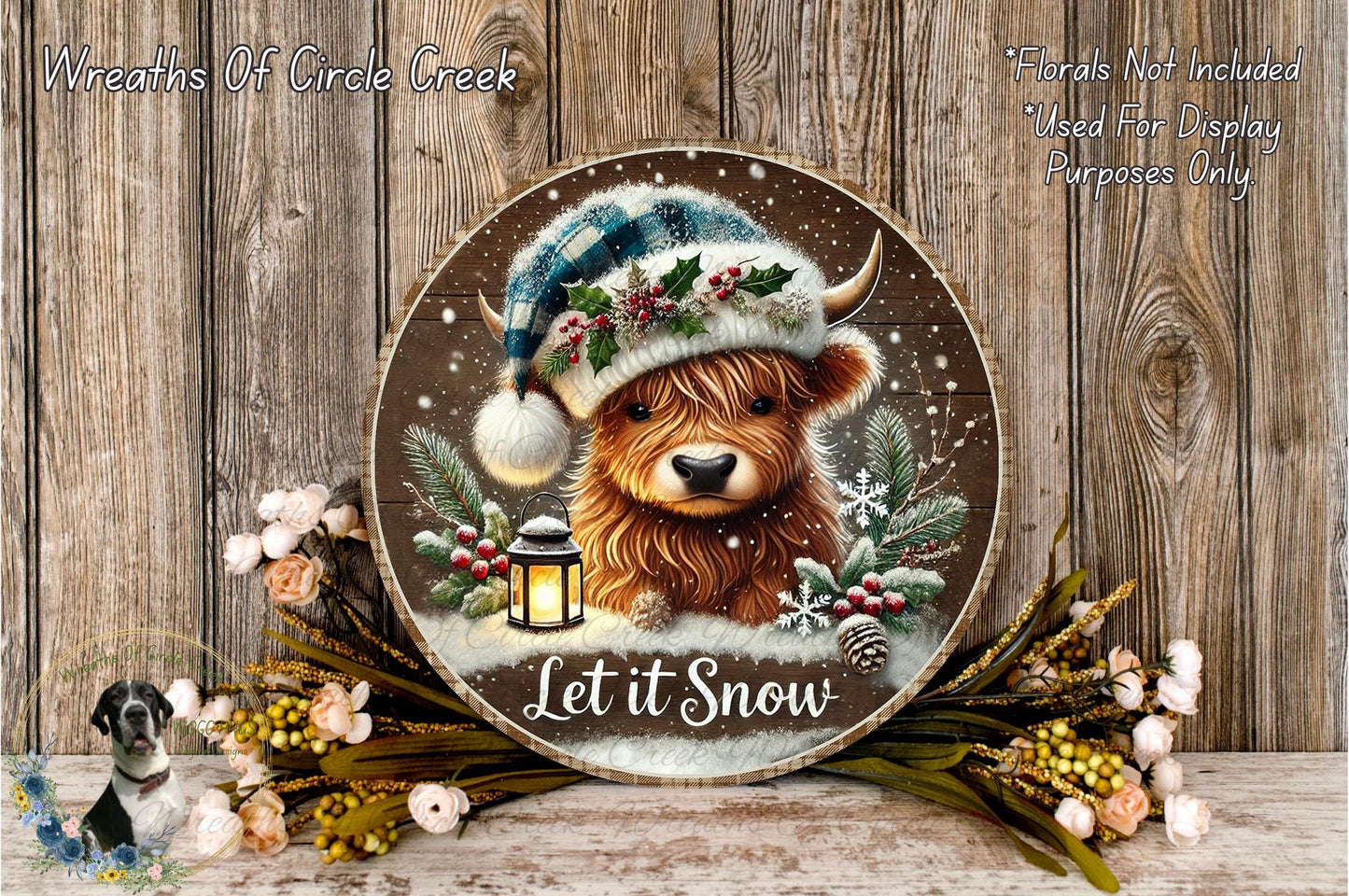 A wooden sign featuring a cartoon cow wearing a winter hat and surrounded by snow, flowers, and a lantern, with the text "Let it Snow" displayed on it.