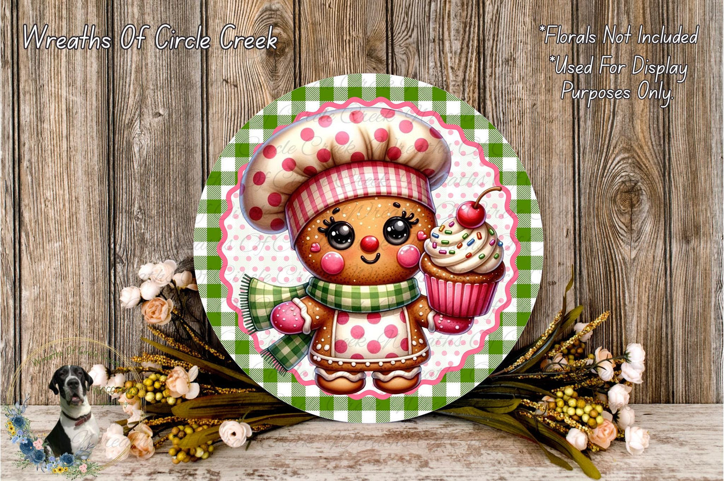 A round wooden plaque featuring a gingerbread man wearing a chef's hat and holding a cupcake, surrounded by a floral arrangement and a wooden background.