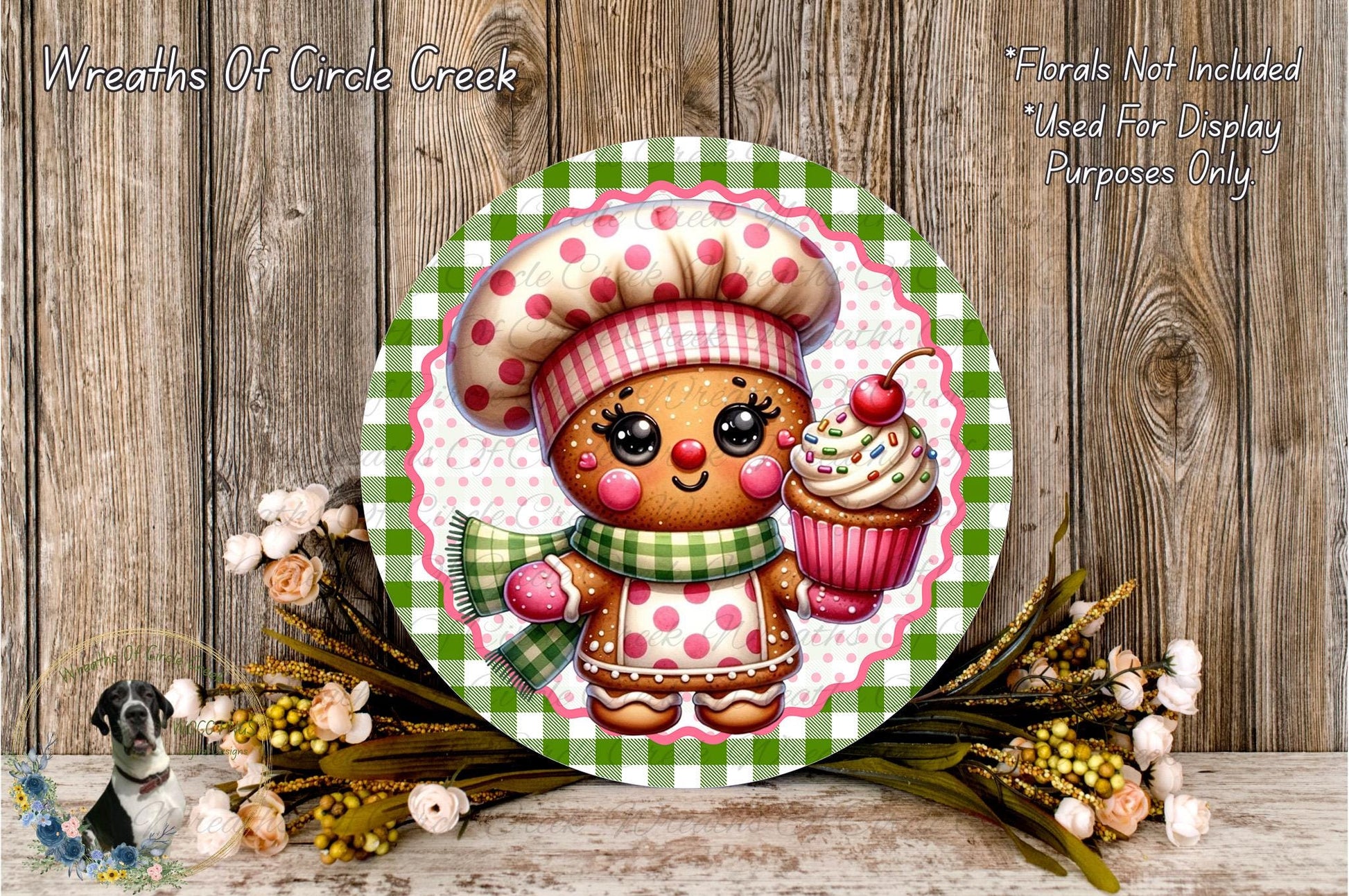 A round wooden plaque featuring a gingerbread man wearing a chef's hat and holding a cupcake, surrounded by a floral arrangement and a wooden background.