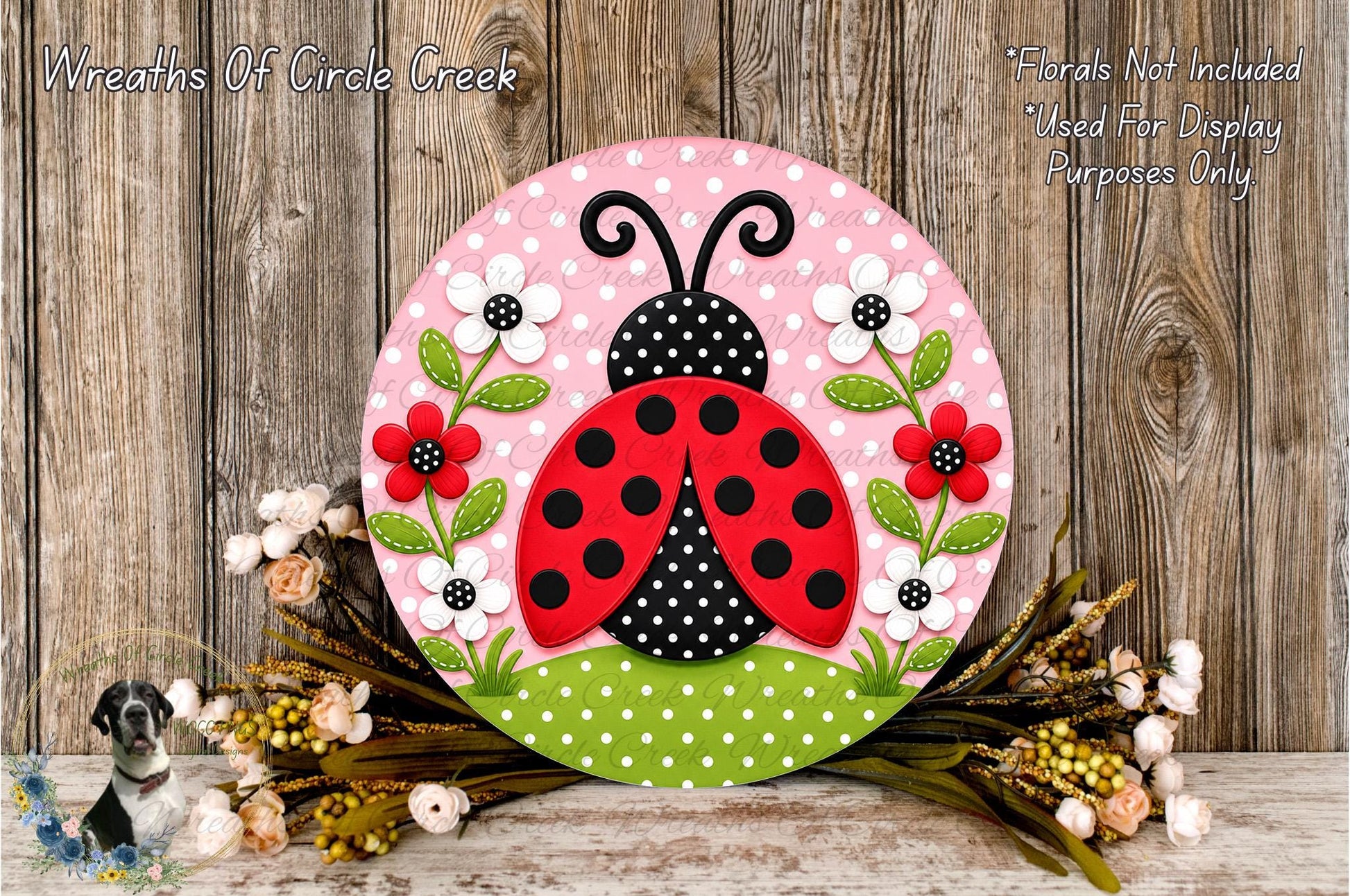 A decorative round sign featuring a red ladybug surrounded by flowers and green leaves, placed on a wooden surface.