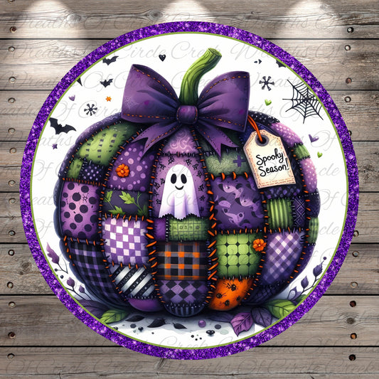 A patchwork pumpkin with a purple bow, surrounded by various Halloween-themed elements such as bats, a spider web, and a ghost.