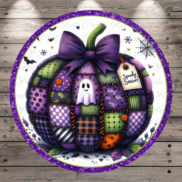 A patchwork pumpkin with a purple bow, surrounded by various Halloween-themed elements such as bats, a spider web, and a ghost.