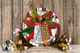 A decorative wreath with a leopard print design, red and green accents, and a red bow. The wreath is surrounded by flowers and placed on a wooden surface.