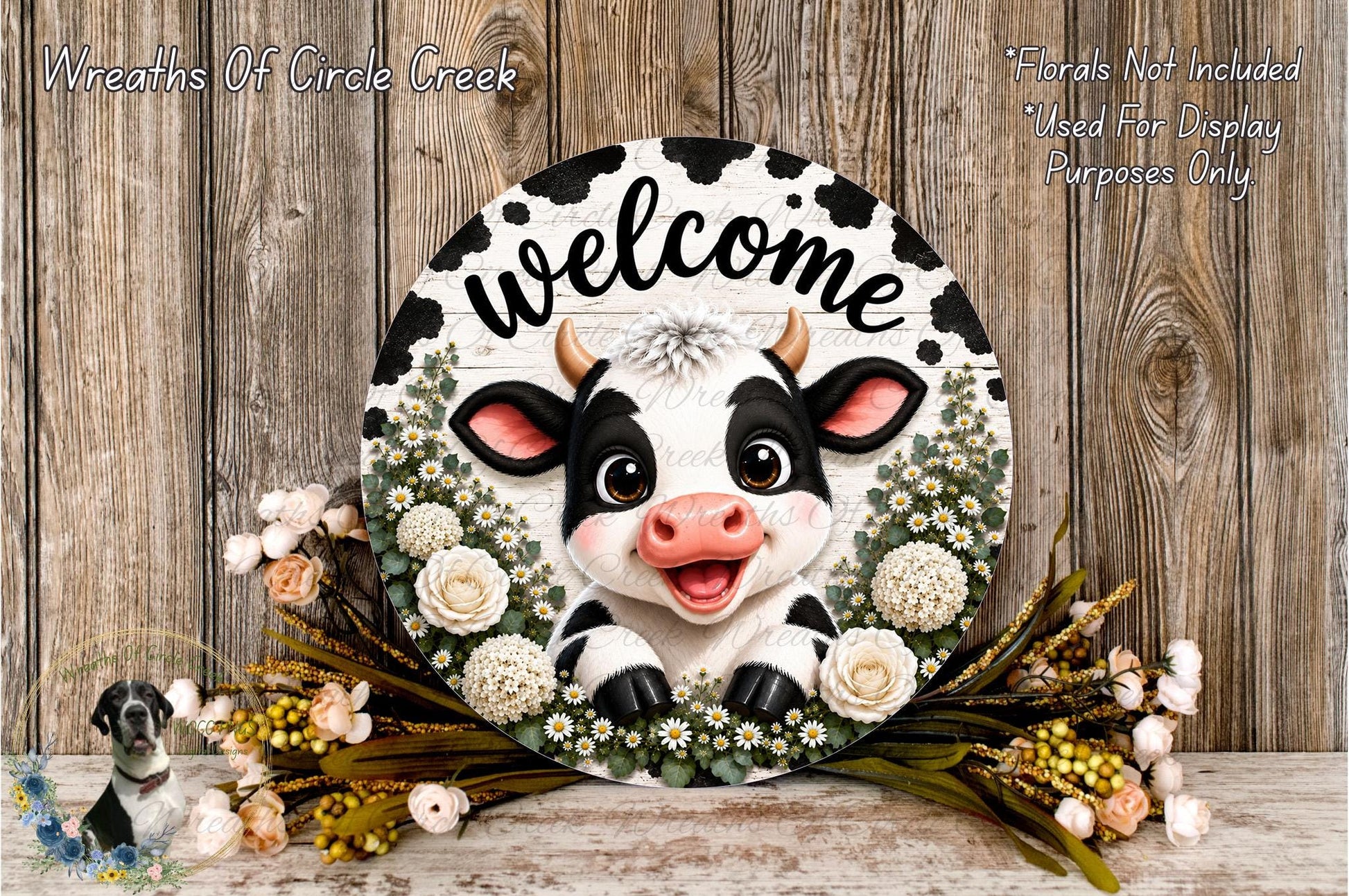 a decorative cow-themed wreath with the word "Welcome" written on it, surrounded by flowers and greenery.