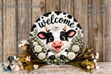 a decorative cow-themed wreath with the word "Welcome" written on it, surrounded by flowers and greenery.