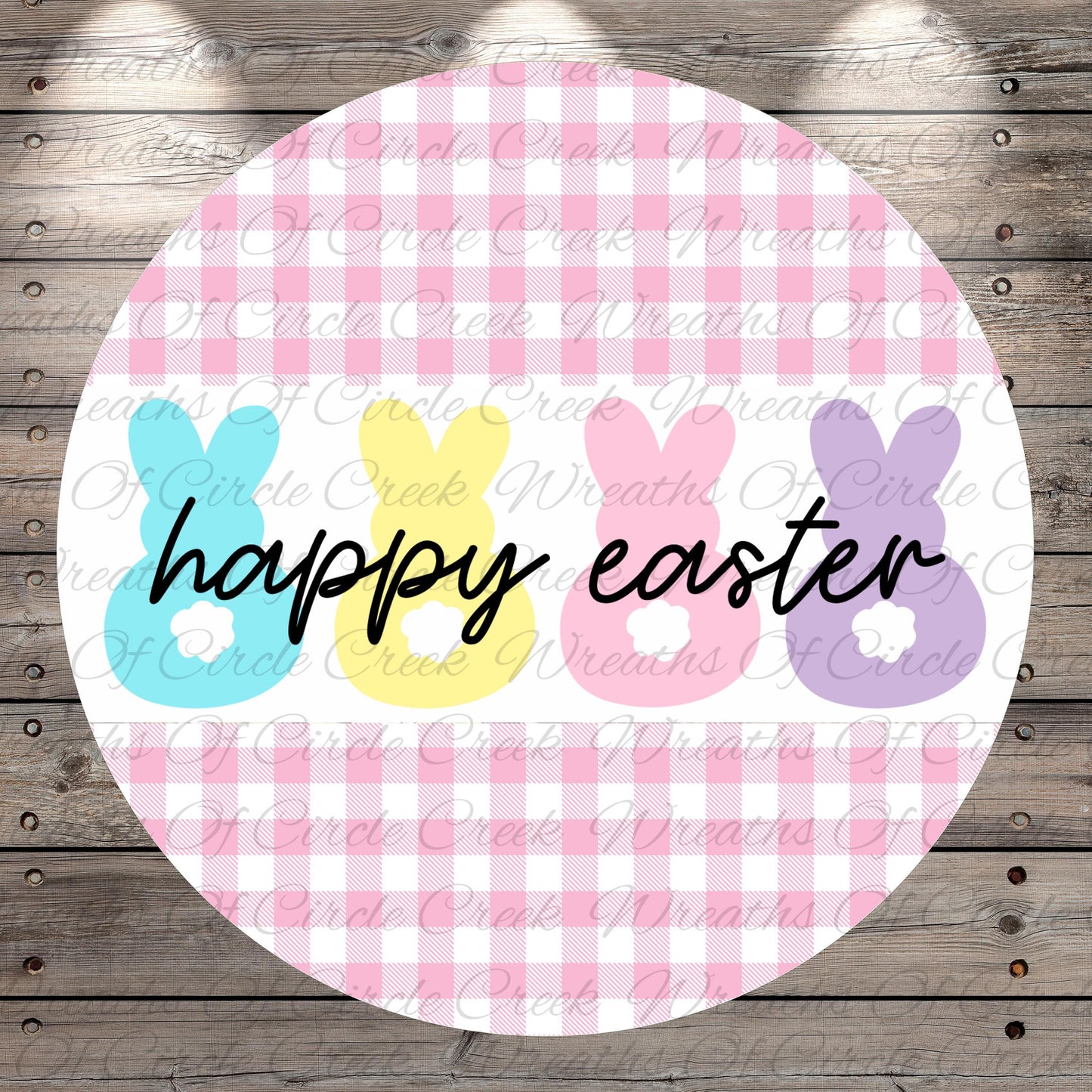 A circular design with a pink and white checkered pattern, featuring three bunny-shaped illustrations in different colors - blue, yellow, and pink. The text "happy easter" is written in black below the bunny illustrations.