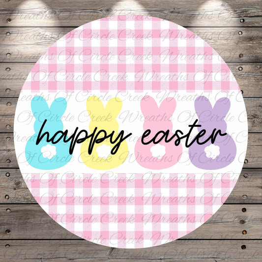 A circular design with a pink and white checkered pattern, featuring three bunny-shaped illustrations in different colors - blue, yellow, and pink. The text "happy easter" is written in black below the bunny illustrations.