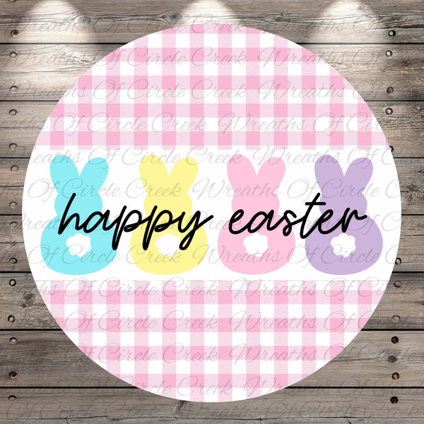 A circular design with a pink and white checkered pattern, featuring three bunny-shaped illustrations in different colors - blue, yellow, and pink. The text "happy easter" is written in black below the bunny illustrations.