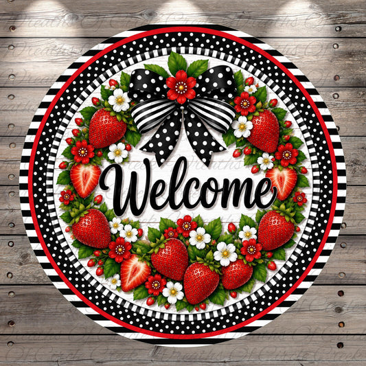 A decorative wreath with a welcoming message, surrounded by red and white flowers and strawberries, is displayed on a wooden background.