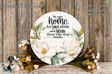 a round wooden sign with a floral design and text, surrounded by a bouquet of flowers and greenery.