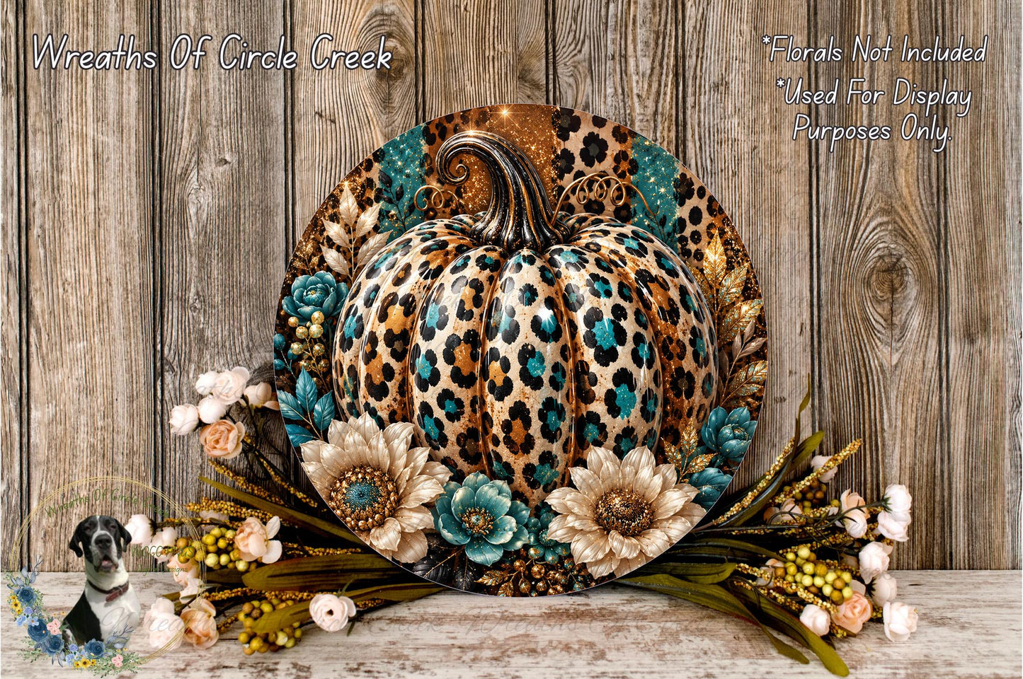 A decorative wreath featuring a leopard print pumpkin surrounded by flowers and foliage, placed on a wooden surface.