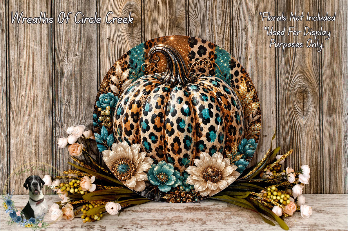A decorative wreath featuring a leopard print pumpkin surrounded by flowers and foliage, placed on a wooden surface.